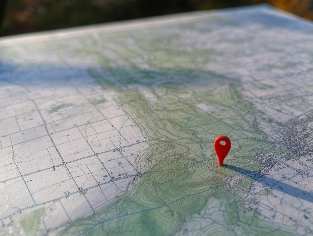 A red pin on a printed topographic map, marking a local business location